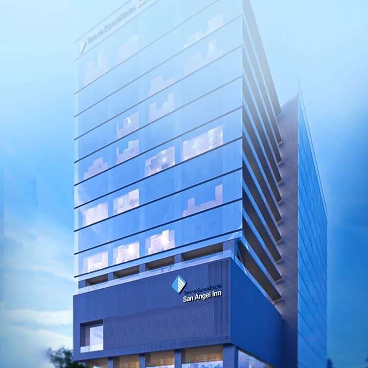 Torre de Consultorios San Ángel Inn Acora del Valle, edificio moderno de vidrio azul con ventanas iluminadas contra cielo nublado